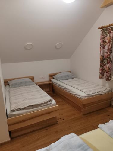 two twin beds in a room with wooden floors at Turistična Kmetija Zgornji Zavratnik in Luče