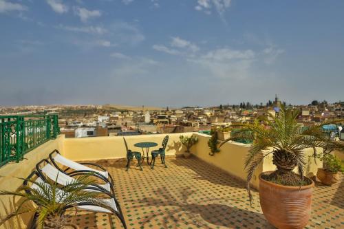 a balcony with chairs and a table and a view of a city at Ryad Mabrouka in Fès