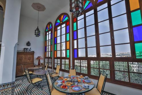a dining room with a table and chairs and stained glass windows at Ryad Mabrouka in Fès