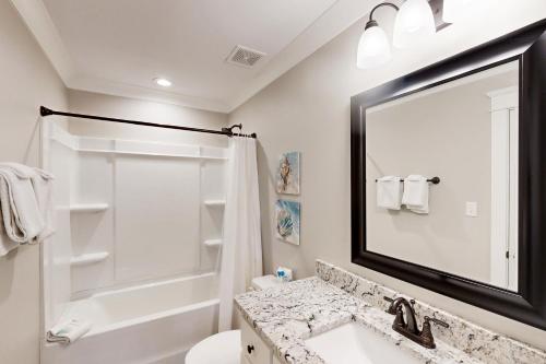 a bathroom with a sink and a shower and a mirror at Beach Cottage in Dauphin Island