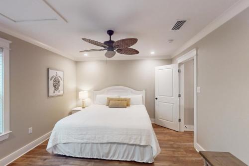 a bedroom with a white bed and a ceiling fan at Beach Cottage in Dauphin Island