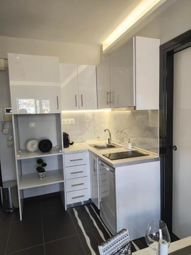 a white kitchen with white cabinets and a sink at K & D Studio in Néa Michanióna