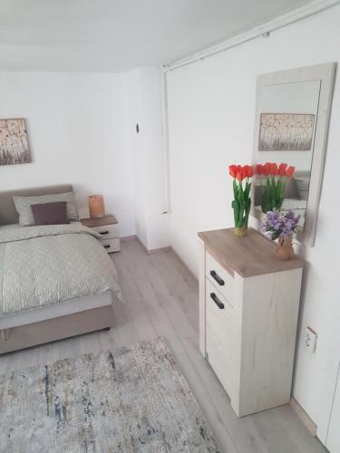 a bedroom with a bed and a dresser with flowers on it at Apartman Memo in Sarajevo