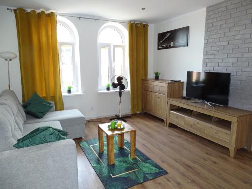 a living room with a couch and a flat screen tv at Apartament Lago in Mrągowo