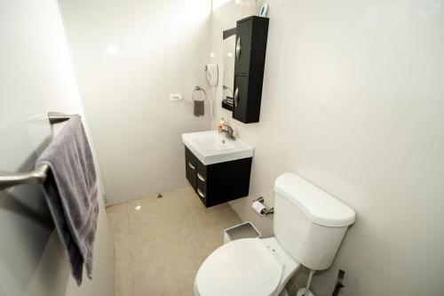 Baño blanco con aseo y lavamanos en Compact Haven with Private Entrance and FREE Parking and Laundry, en Ponce