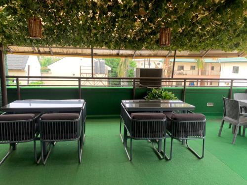 a patio with tables and chairs and a green floor at Rivalex Apartment and Rooftop in Abuja