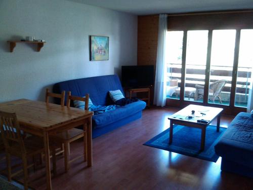 Appartement À La Jorette-Torgon في Torgon: غرفة معيشة مع أريكة زرقاء وطاولة