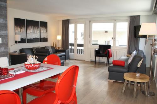 ツェルマットにあるCentral & Elegant Apartments,partially with Fireplace, by Zermatt Rentalのリビングルーム(テーブル、赤い椅子付)