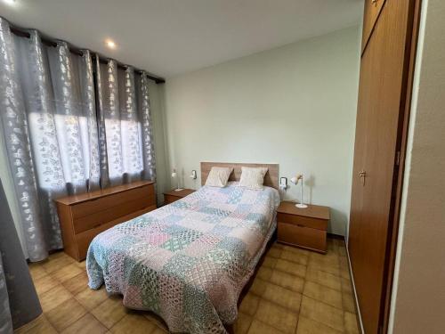a bedroom with a bed with a quilt on it at Apartamentos Coma-Ruga con vistas al mar in Comarruga