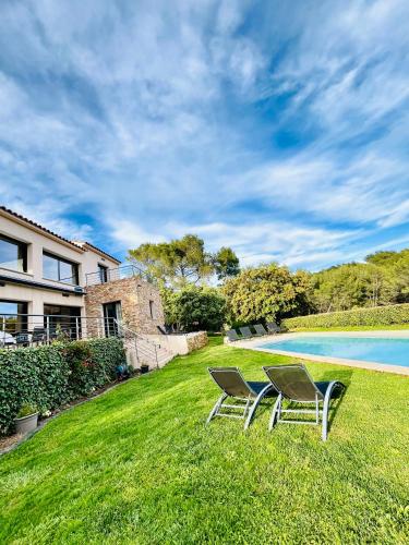 2 chaises assises dans l'herbe à côté d'une piscine dans l'établissement La grange des amoureux piscine jacuzzi et massages, au Beausset