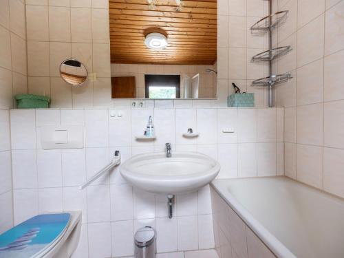 a white bathroom with a sink and a bath tub at Serene Holiday Home in Nehren in Nehren
