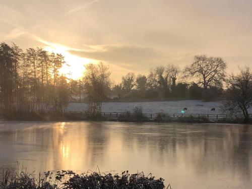 a frozen pond with the sun setting in the background at Astwell Mill in Helmdon