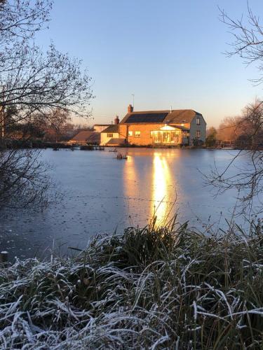 a house on a lake with snow on the water at Astwell Mill in Helmdon