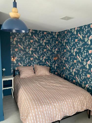 une chambre avec un lit avec un papier peint fleuri dans l'établissement Petite maison centre ville, à Coulommiers