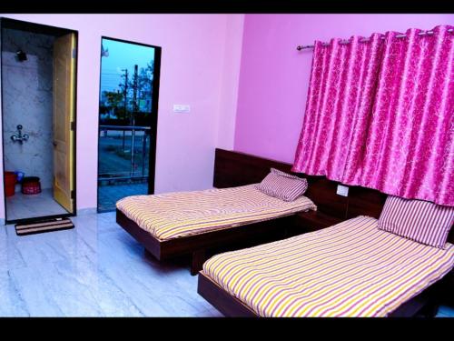 a room with two beds and a window with pink curtains at Krishna yatri Niwas in Akalkot