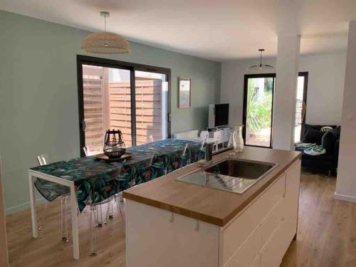 une cuisine avec une table et un comptoir dans l'établissement Lacanau Océan, grand logement, grandes terrasses, pinède, à Lacanau-Océan