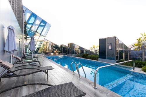 a swimming pool with chairs next to a building at GLOBALSTAY J One Tower Apartments at Pearl of UAE in Dubai