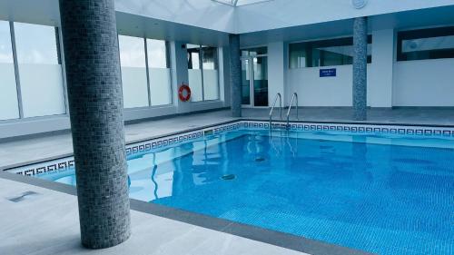 a large swimming pool with blue water in a building at Chalet 26 Widemouth Bay in Bude