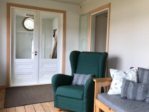 a living room with a green chair and a door at Naantalissa idyllinen merenrantatalo, OnnenPoukama in Naantali