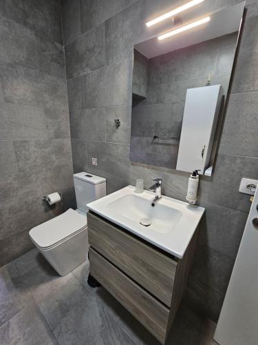 een badkamer met een wastafel, een toilet en een spiegel bij Brian's Apartment in Tirana in Tirana