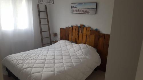 une chambre avec un lit blanc avec une tête de lit en bois dans l'établissement Le calme à Léon, à Léon