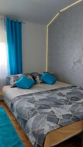a bed with blue pillows on it in a bedroom at Plavi Tirkiz in Pančevo