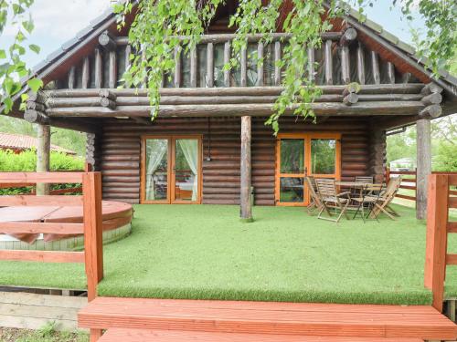 a log cabin with a table and chairs in front of it at 10 Duck Lagoon in Tattershall
