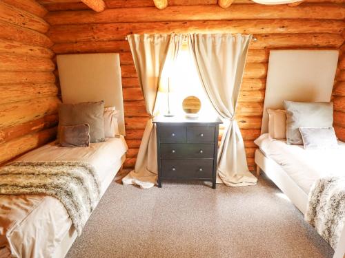 2 camas en una cabaña de madera con ventana en 10 Duck Lagoon, en Tattershall