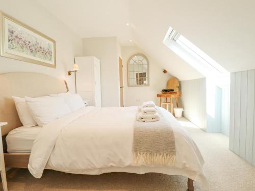 a white bedroom with a large white bed and a window at The Smithy in Grimsby