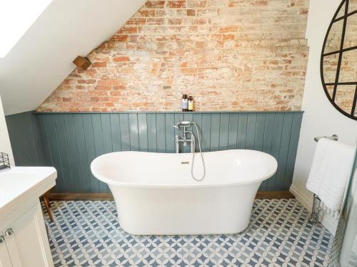 a white bath tub in a bathroom with a brick wall at The Smithy in Grimsby