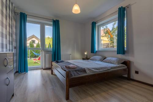 a bedroom with a bed and a window with blue curtains at Pokoje Goscinne AnMar in Krościenko