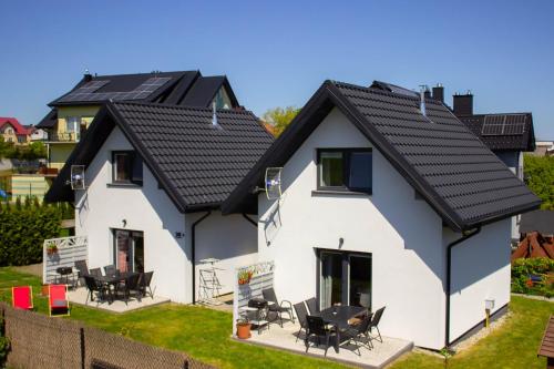 a white house with black roof at Domki u Marty - Władysławowo in Władysławowo