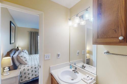 uma casa de banho com um lavatório, um espelho e uma cama em The Landing 203 by Meyer Vacation Rentals em Gulf Shores