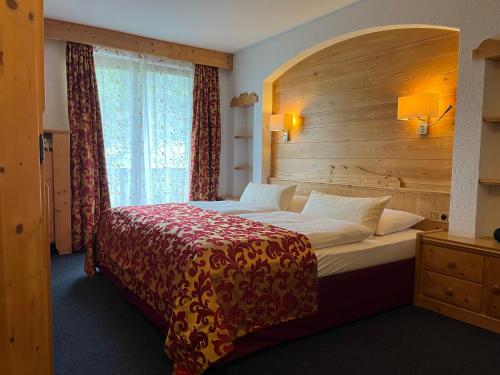 a bedroom with a large bed with a wooden wall at Alpenhof Wallgau in Wallgau