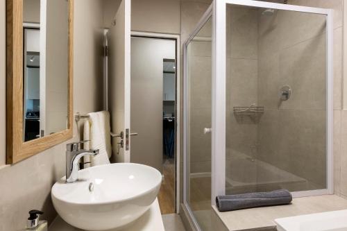 a bathroom with a white sink and a shower at Nivica 54 Luxury Apartment in Langebaan