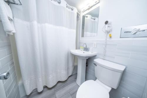 a white bathroom with a toilet and a sink at Nassau Inn in Wildwood Crest