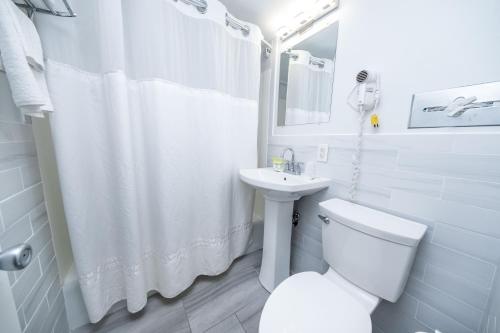 a white bathroom with a toilet and a sink at Nassau Inn Beachfront in Wildwood Crest