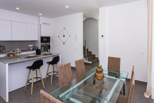 cocina y comedor con mesa de cristal y sillas en Casa Daniela Lanzarote piscina climatizada, barbacoa y wifi free, en Tahiche