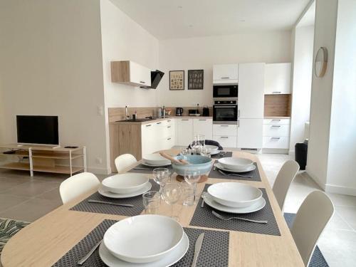 une salle à manger avec une table avec des assiettes et des verres à vin dans l'établissement Bassin à flot, appartement lumineux et central, à Lorient