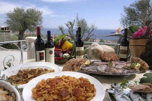 a table with plates of food and bottles of wine at Hotel Brancamaria in Cala Gonone