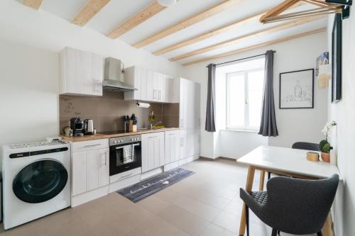 a kitchen with a washing machine and a table at Tranquil Wachau Escape - 45m2 with Outdoor Terrace in Mautern