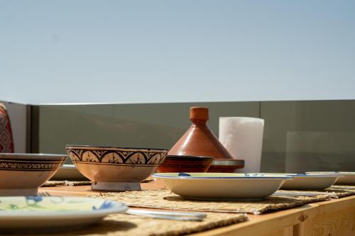 a table with bowls and plates on a table at Tayyurt Surf Camp Tamraght Aourir in Awrir