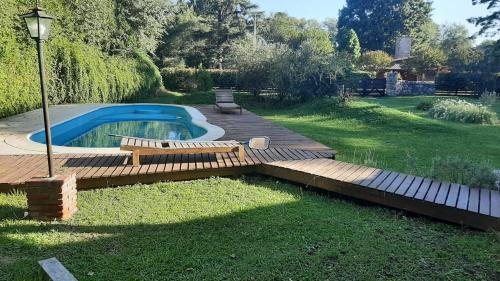 un patio trasero con piscina y terraza de madera en Cabaña Odanak en Villa General Belgrano