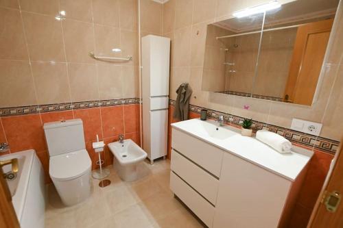 Un baño con inodoro, lavabo y espejo. en Tambarón Bay, en Calpe