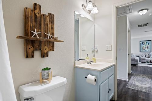 ein Badezimmer mit einem WC und einem Waschbecken mit einem Spiegel in der Unterkunft Deep Blue Yonder - Ping-pong! Bikes! Games! Cute and cozy 3-bed, 2-bath home in the heart of Crystal Beach! in Crystal Beach