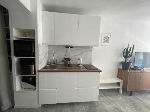 une cuisine avec des armoires blanches et un comptoir dans l'établissement Appartement à 3mn de la Promenade Des Anglais, à Nice