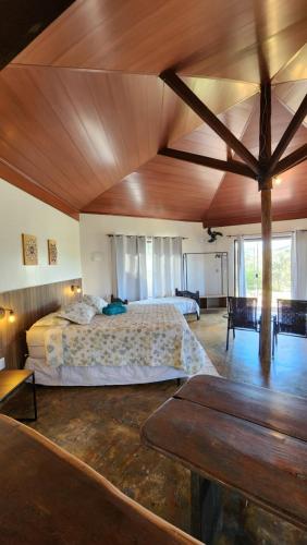 um quarto grande com uma cama grande e um tecto de madeira em Bangalôs Canto da Coruja em São Jorge