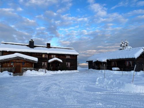two wooden buildings with snow on them in a field at Knappgården in Särna