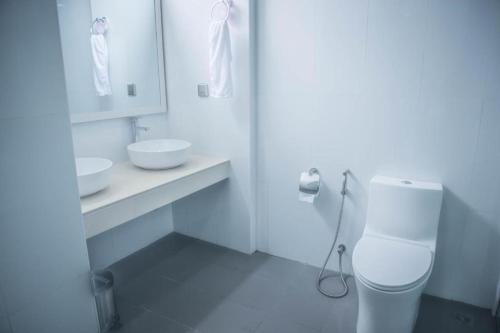 a white bathroom with a toilet and a sink at Morus Bliss - Divers' Preferred Hotel in Maradhoofeydhoo