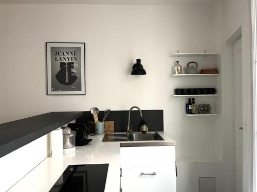 une cuisine blanche avec un évier et un comptoir dans l'établissement Charming appartement Moulin Rouge, à Paris